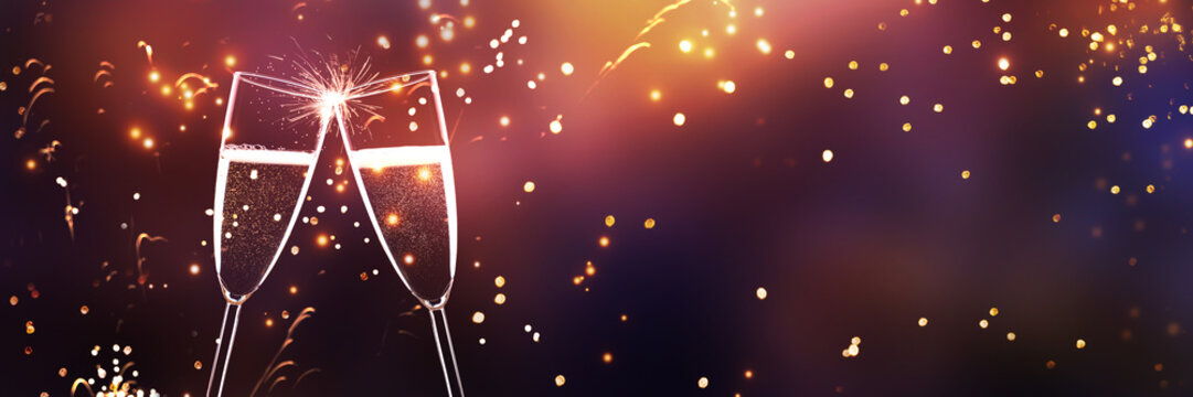 two cklinking champagne glasses isolated on abstract fireworks background banner with cheerful colors and copy space, greeting card for christmas, new years eve and holiday season
