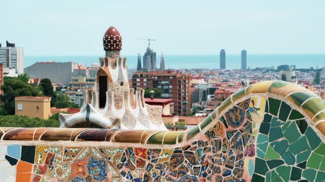 Panoramic view of Barcelona city skyline overlooking mosaic bench at Park Guell.