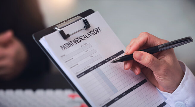 Focused hand writes patient medical history on clipboard showcasing efficient administration workflow during professional clinic checkup