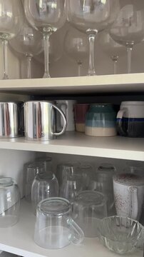 Open kitchen cabinet shelves with glasses and mugs