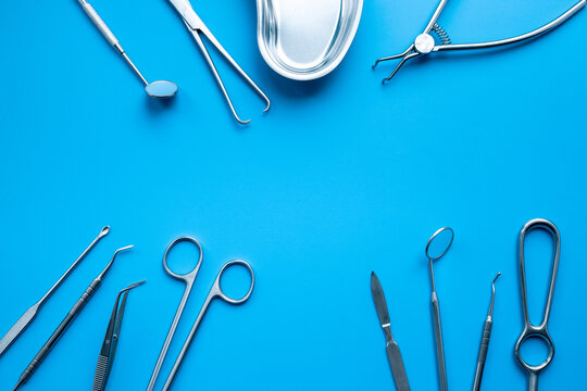 A lot of stainless surgical instruments and tools on blue table, top view. Medical background