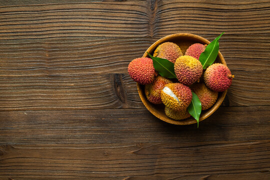 Exotic lychee fruit with green leaves in wooden bowl, top view. Healthy vegetarian meal