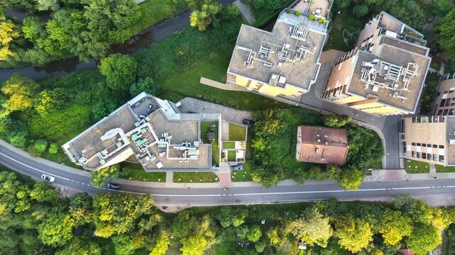 Aerial view of modern residential buildings surrounded by lush greenery and a winding road, showcasing the architectural layout and natural landscape in a suburban area