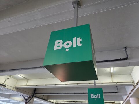 July 1st 2026, Poland. Green hanging cubic sign with white Bolt logo in an underground parking lot or indoor transport hub with ceiling structures.