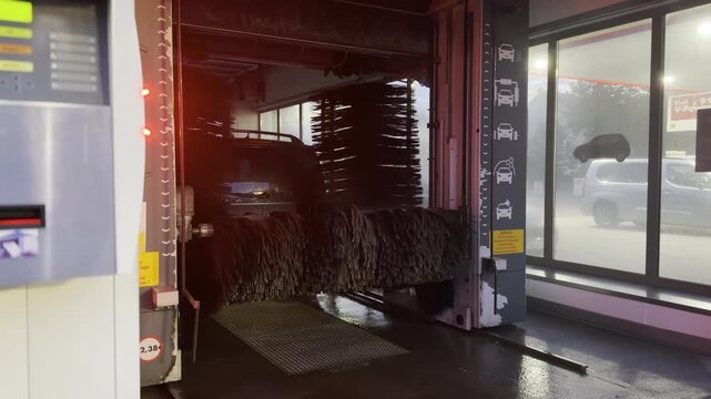Automatic car wash interior with large brush cleaning a vehicle in a wet service bay.