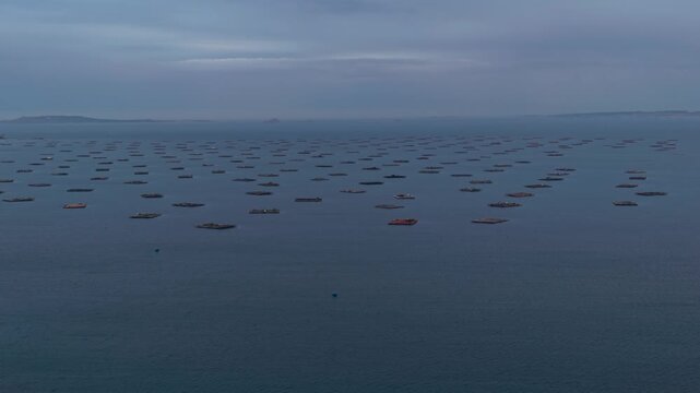 Aerial - Rows of floating aquaculture rafts spread across calm grey sea on the Spanish coast