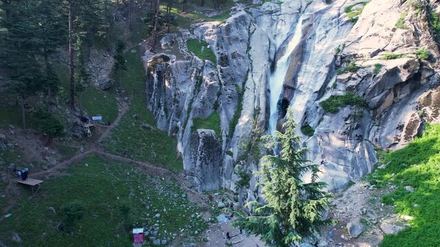 Waterfall plunges down a rocky cliff with visitors at its base in Upper Dir District, Khyber Pakhtunkhwa, Pakistan