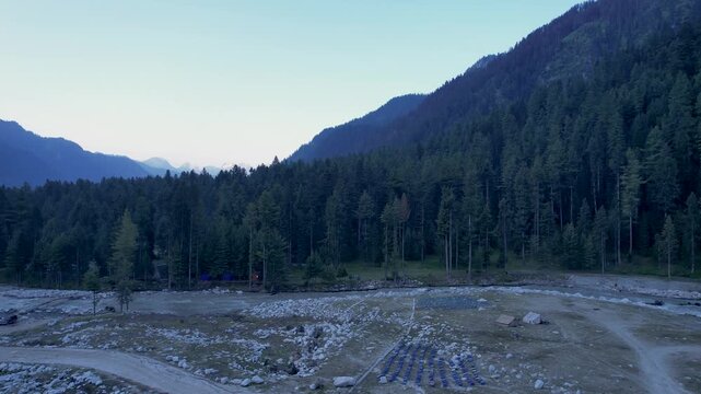 Dense conifer forest borders a rocky valley beneath mountains in Upper Dir District, Khyber Pakhtunkhwa, Pakistan