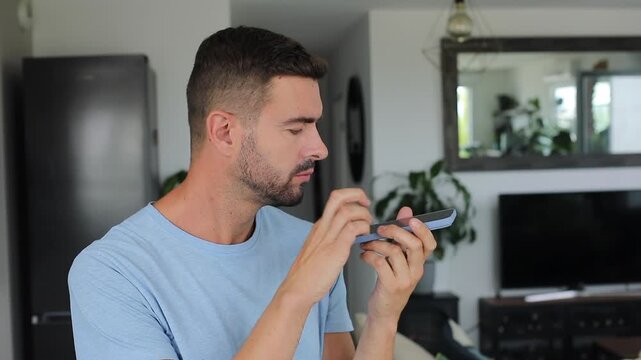 Man listening to confusing audio messages on smartphone in disbelief.
