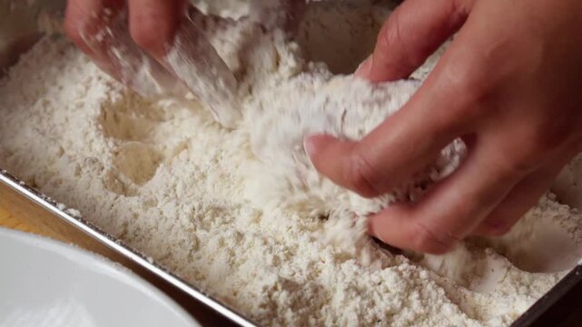 Raw chicken drumstick coated in flour inside metal tray