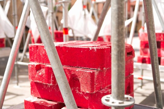 Red concrete counterweight blocks used as ballast for temporary scaffolding construction stability