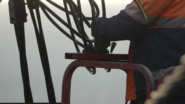 Worker rigging maintenance, industrial employee operating heavy equipment controls at sunrise or misty construction site