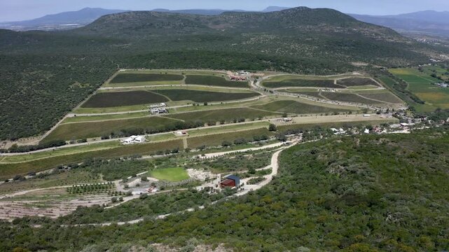 Aerial panorama of vineyards in Queretaro Mexico surrounded by rolling hills, drone panoramic orbit establishing of winding roads