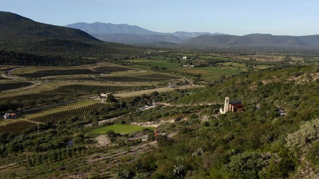 Wide aerial backdrop of vineyards across Queretaro valley and surrounding mountains, drone establishing overview