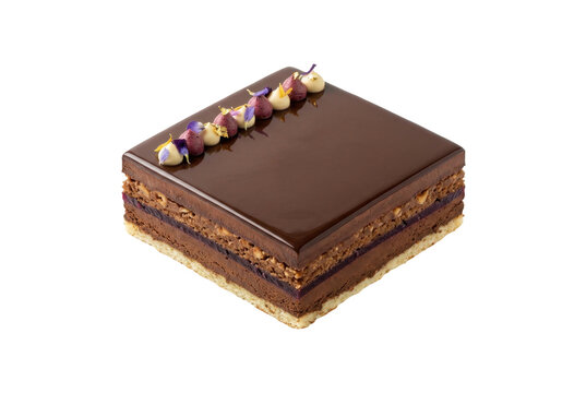 Square chocolate opera cake with floral garnish.