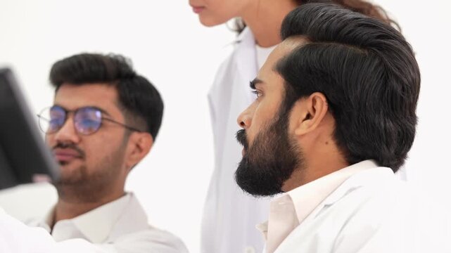 Team of professional medical researchers discussing data together on monitor screen at laboratory while conducting scientific analysis for health report