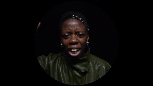 Portrait of young adult African American woman talking, gesturing, and laughing inside circular frame on black background. Footage is perfect for diverse marketing campaigns and social media ads
