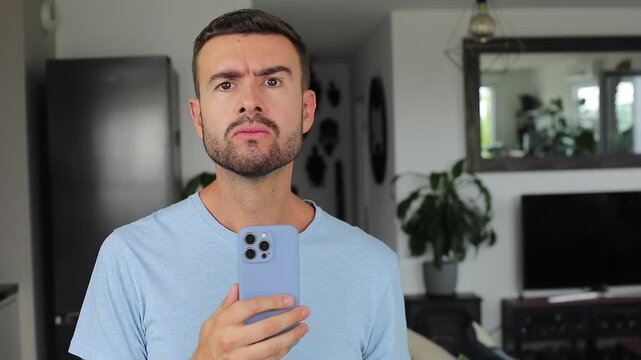 Serious man noticing camera and recording with smartphone in suspicious reaction