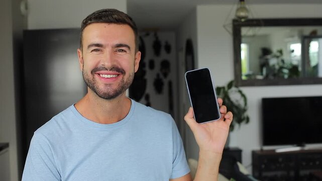Happy man showing modern smartphone screen and smiling directly at camera