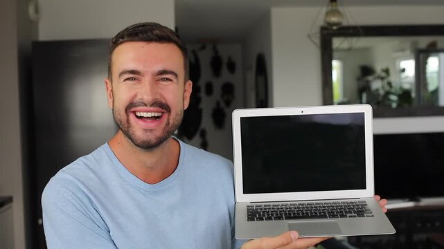 Happy man opening modern laptop computer and smiling at camera screen while seeing something funny