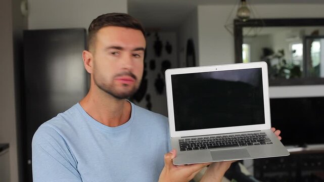 Man opening modern laptop computer and looking at camera with neutral expression 