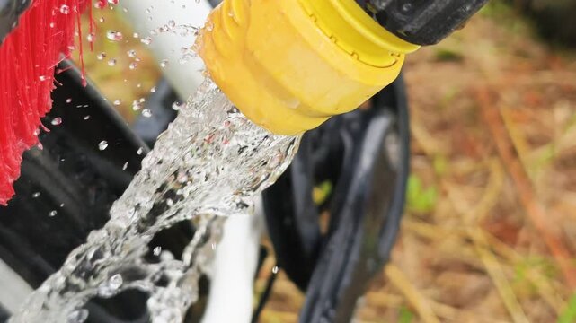 Bike detailing involves brush cleaning chain thoroughly, water splashing away dirt and grime. Bike detailing ensures sports equipment stays spotless, improving performance and lifespan overall.