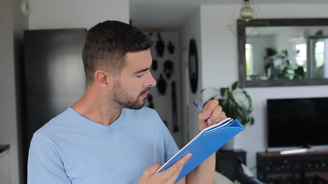 Handsome man sitting home attentively listening and taking personal notes