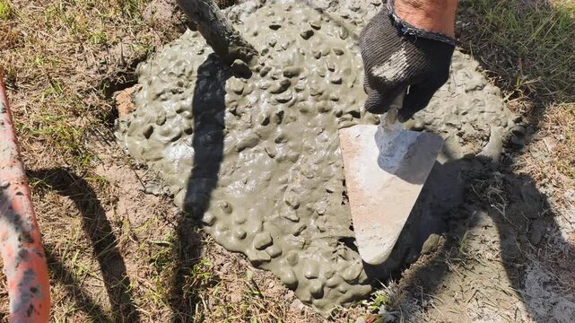 Trowel work spreads wet concrete smoothly across ground, shaping surface for solid foundation. Trowel work requires steady hands and skilled technique, essential for professional construction quality.