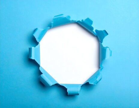 Close up of torn blue paper revealing white space in a geometric shape