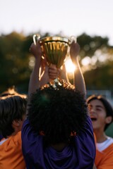Naklejka premium Youth soccer team holding championship trophy at sunset for victory celebration banner and sports background
