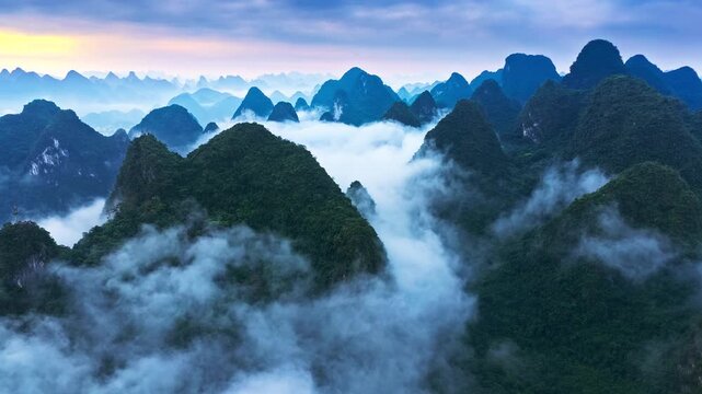 Misty karst peaks rise above layered clouds in Guilin, Guangxi, China, offering a serene landscape for travel, tourism, nature, and environmental concepts.