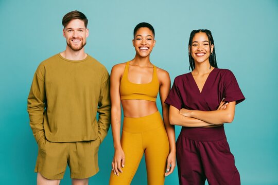 Smiling diverse group of young adults in colorful activewear and loungewear for wellness and lifestyle banner background and studio portrait use