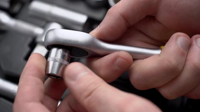 Mechanic hands attaching metal drive socket head to quick-release ratchet wrench handle close-up