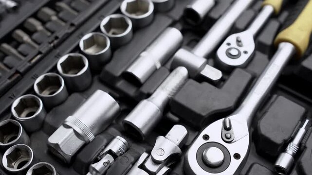 Top view close-up of rotating open toolbox with complete set of socket wrenches, ratchets, and drive bits