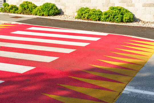 Modern pedestrian crossing painted with bright red pavement and bold white stripes designed to improve road safety and pedestrian visibility in an urban environment