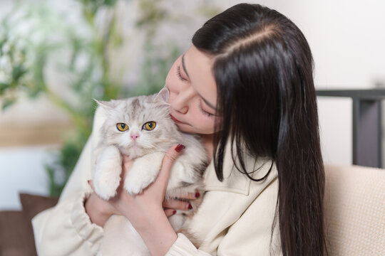 Asian woman hugging cute fluffy cat at home for pet companionship lifestyle