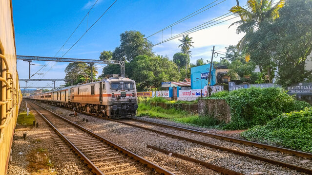 Varkala, Kerala, India &ndash; July 25, 2026: An Indian Railways passenger train powered by a WAP-7 electric locomotive crosses another train near Varkala Sivagiri station in Kerala