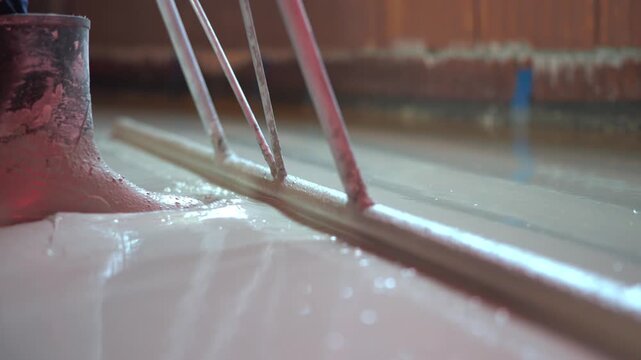 Construction worker spreading self-leveling screed on floor