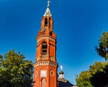 Red brick bell tower of Russian Orthodox church against clear blue sky in Sergiyev Posad
