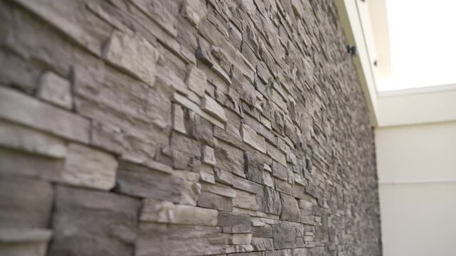 Closeup of layered stone wall with rough texture neutral gray tones. Soft natural light from window highlights depth dimension. Ideal for interior design, architecture, background use
