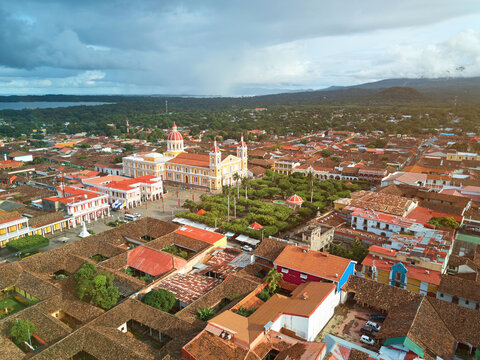 Aerial view of the Cathedral of Granada surrounded by historic colonial architecture, red-tiled rooftops, and lush trees in the city center of Granada, Granada, Nicaragua.