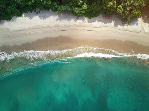 Aerial view of Playa La Redonda with turquoise water, white sand beach, and lush green trees along the coastline in Tola, Rivas, Nicaragua.