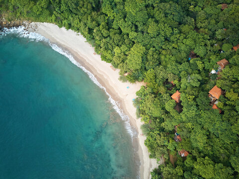 Aerial view of Playa La Redonda with turquoise water, sandy beach, and lush tropical forest with hidden villas in Tola, Rivas, Nicaragua.