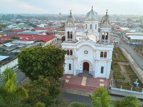 Aerial view of the Basilica of San Sebastian featuring its white facade, twin towers, and surrounding urban landscape with red-roofed buildings Diriamba, Carazo, Nicaragua.