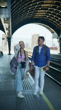 Young tourists stand on a train station platform, preparing for their journey. They walk away, eager to explore their next travel destination.