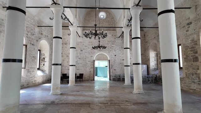 White columns line the spacious, stone-walled interior of the historic Yalı Church in &Uuml;nye, Ordu, featuring arched windows and chandeliers.