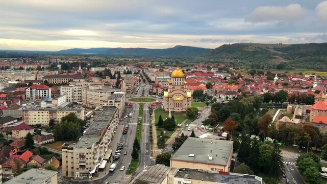 Aerial view of Fagaras city showing cathedral and downtown architecture in Romania during cloudy day.