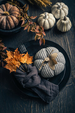 Cozy autumn table setting with knitted pumpkins and fall leaves