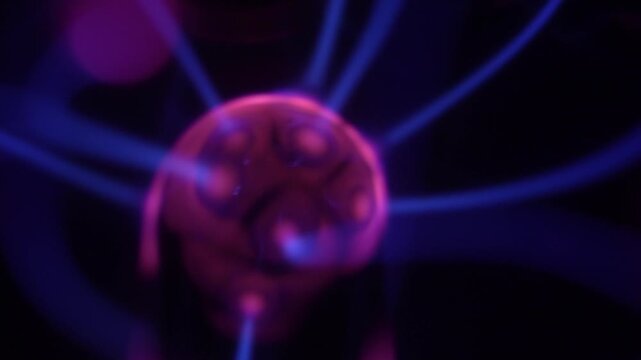 A close-up of a plasma ball coil that creates energy beams in shades of purple.