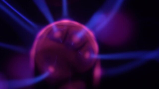 A close-up of a plasma ball coil that creates energy beams in shades of purple.